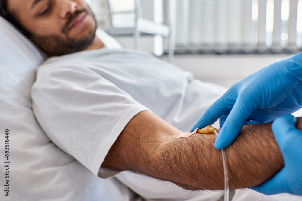 cropped view of african american nurse inserting catheter into arm of her indian patient, healthcare cropped view of african american nurse inserting catheter into arm of her indian patient, healthcare