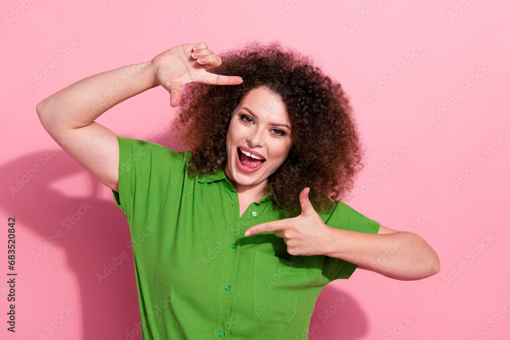Photo of cheerful positive young woman dressed green shirt smiling showing hands photo frame isolated pink color background Photo of cheerful positive young woman dressed green shirt smiling showing hands photo frame isolated pink color background