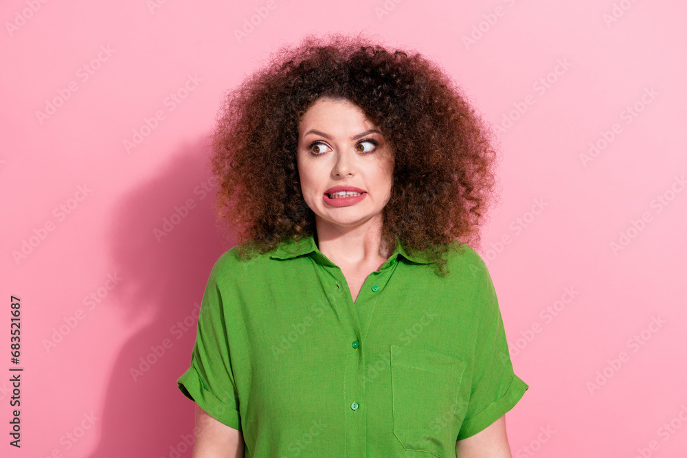Photo of funky nervous young woman dressed green shirt looking empty space isolated pink color background Photo of funky nervous young woman dressed green shirt looking empty space isolated pink color background