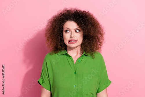 Photo of funky nervous young woman dressed green shirt looking empty space isolated pink color background