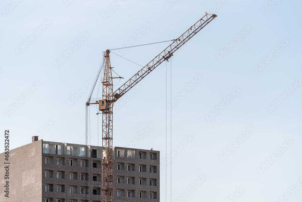 A construction site with a tower crane erecting a new house. A construction site with a tower crane erecting a new house.