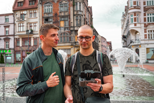 Obraz na płótnie Two brothers operating a drone in the old city center. w salonie