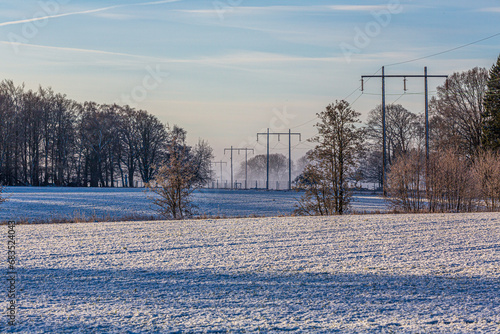 Power lines through snow-covered farmland