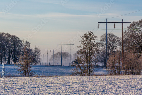 Power lines through snow-covered farmland