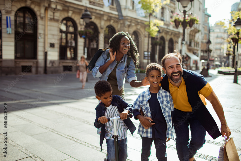 Happy multiracial couple walking in the city with sons