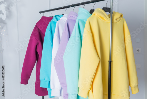 Sweatshirts on hangers in the clothing store for sale. Row of colorful cashmere hoodies for youth. Multi-colored sweatshirts in a clothes stand in the mall.fashion woman's sweats hoodie © Yulia