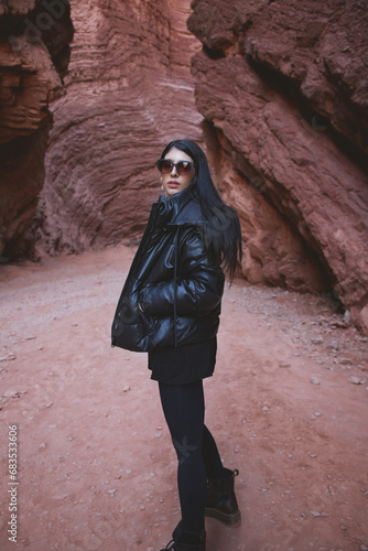 Retrato de mujer joven morocha vestida de negro parada en medio de La Garganta del Diablo, Cafayate, Salta