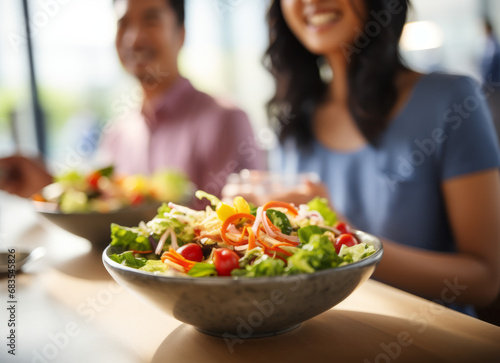 Blurred Young cheerful Asian couple in sportswear actively communicating and cooking diet salad after workout. Health, active lifestyle, motivation.