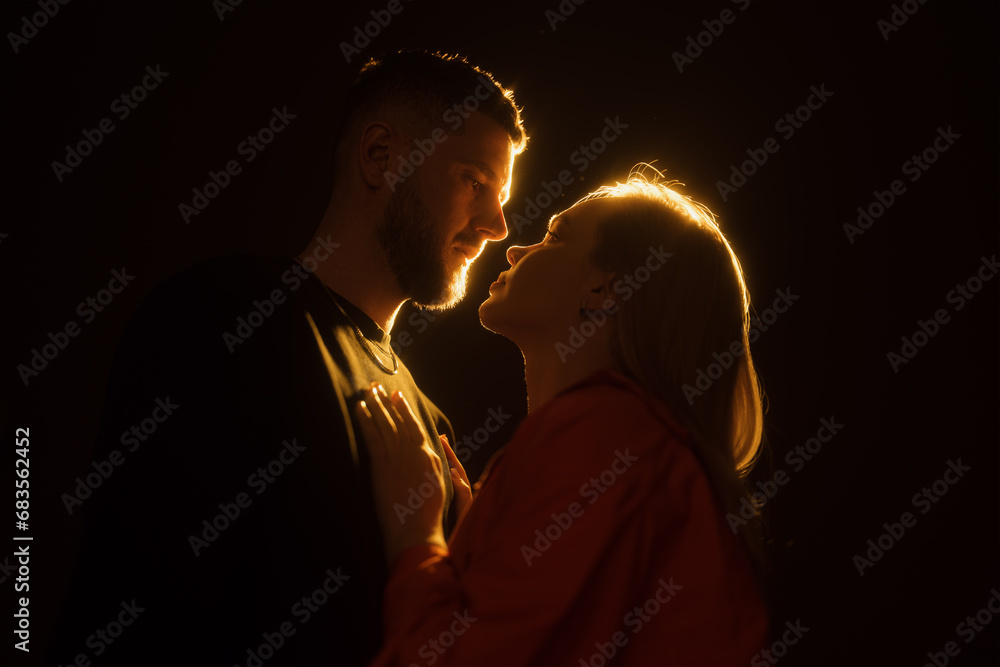 A silhouette of a loving couple about to kiss, surrounded by a warm golden halo of light, creating an intimate atmosphere