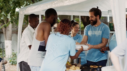 Multiethnic charitable organization provides free food and provisions to the homeless and crippled. Black woman wearing a blue t-shirt aiding a helpless, crutch-wielding african american guy.
