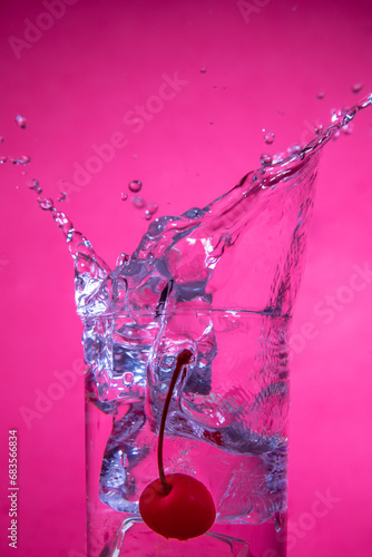 Water splash with cherry and ice on pink photo