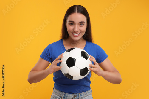 Happy fan holding soccer ball on yellow background © New Africa