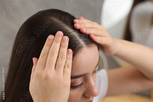 Quadro su tela Woman examining her hair and scalp on blurred background, closeup