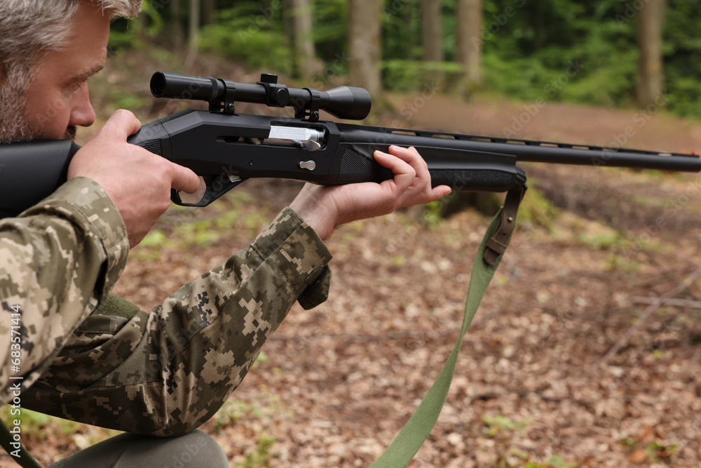 Man wearing camouflage and aiming with hunting rifle in forest, closeup Man wearing camouflage and aiming with hunting rifle in forest, closeup