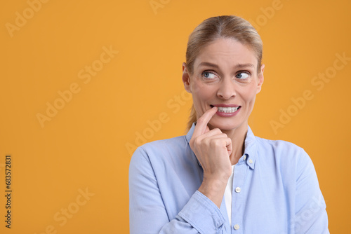 Embarrassed woman on orange background. Space for text
