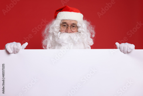Santa Claus holding blank poster on red background. Space for text © New Africa