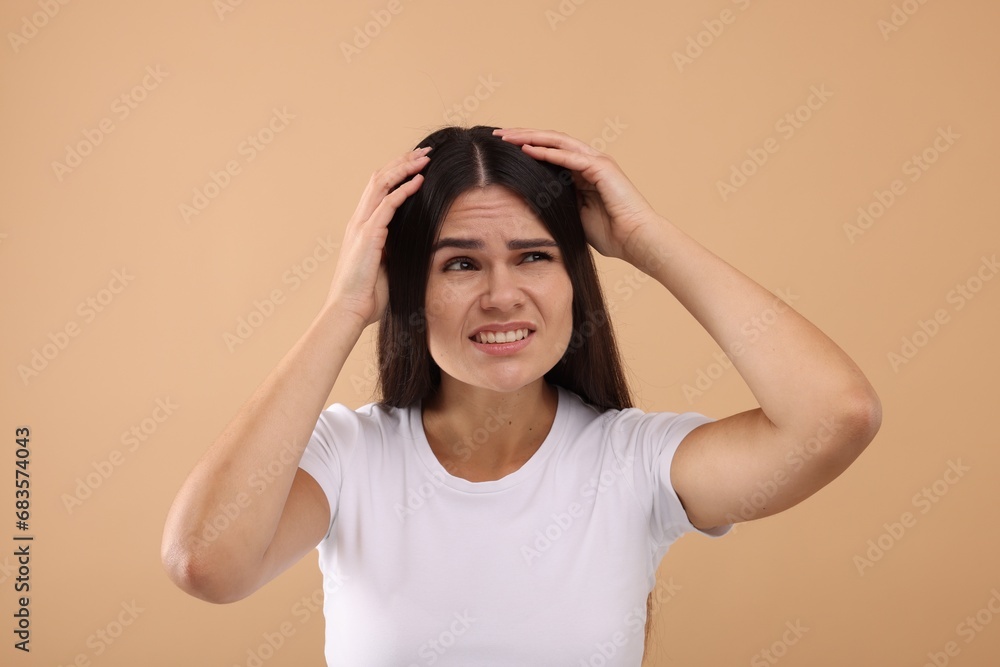 Emotional woman examining her hair and scalp on beige background Emotional woman examining her hair and scalp on beige background