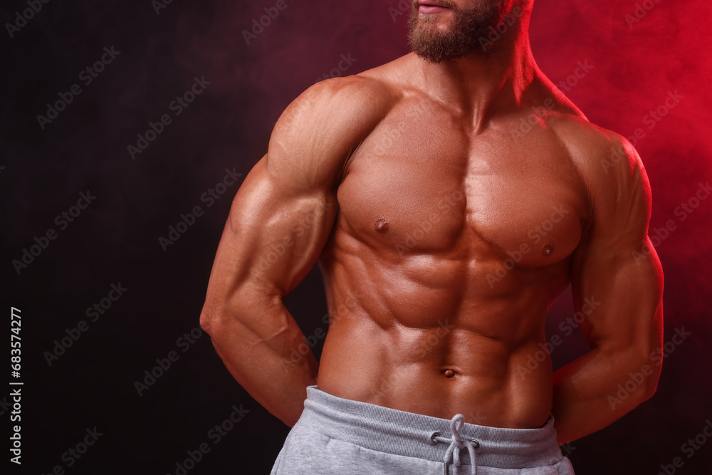Young bodybuilder with muscular body in smoke on color background, closeup