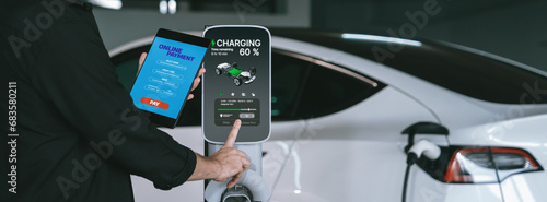 Young man travel with EV electric car to shopping center parking lot charging in downtown city showing urban sustainability lifestyle by green clean rechargeable energy of electric vehicle innards