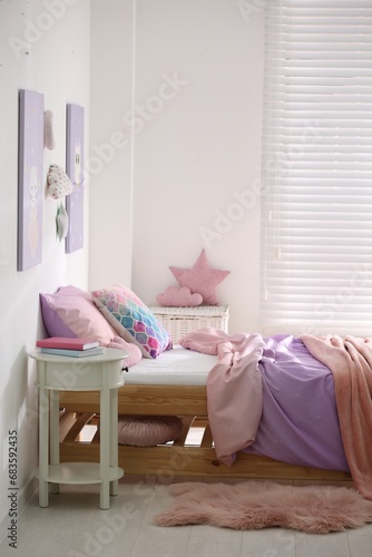 Bed with colorful linen in stylish children's room. Interior design