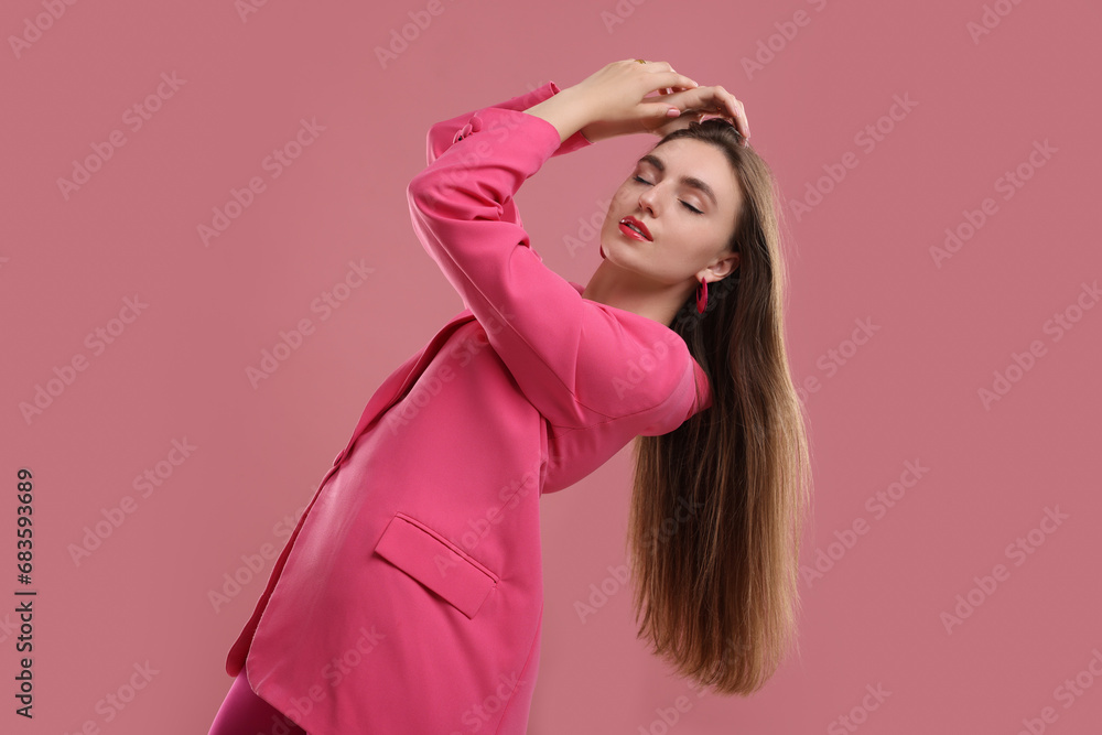Fototapeta premium Beautiful young woman in pink clothes on color background
