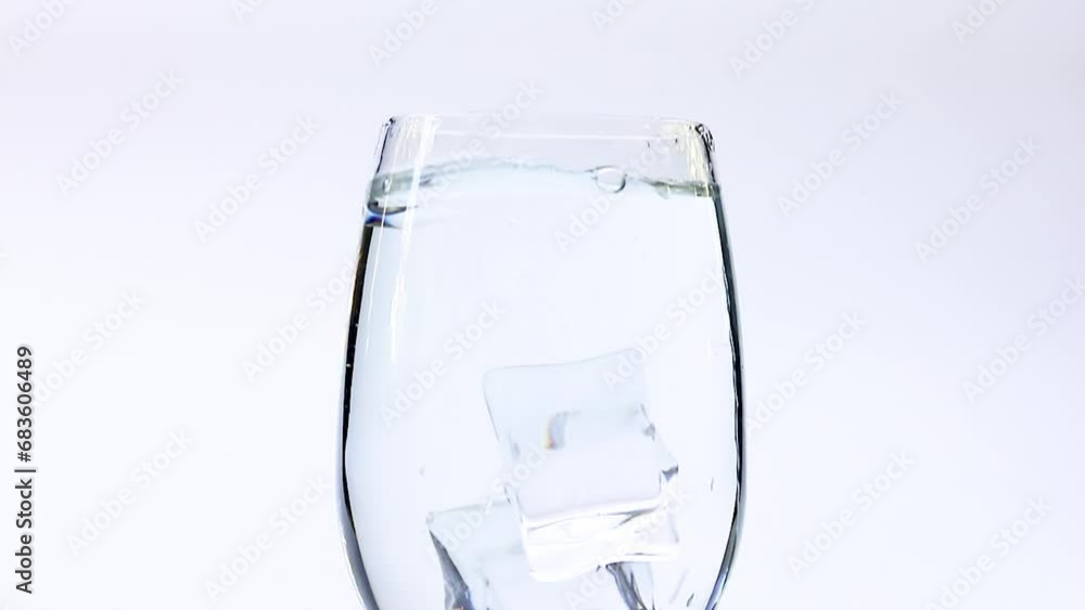 Put ice cubes in a glass of water. Ice cubes fall into pure water. Summer cold drink, water, bubbles 