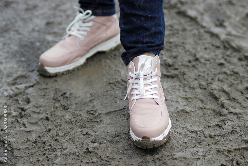 Woman wears new sneaker shoes, now covered in mud, while embarking on an adventurous hike in nature