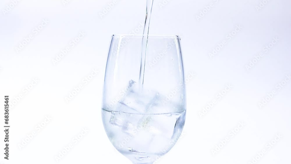 Pour clear water into a glass with ice cubes. Summer cold drink, water, bubbles on white background Pour clear water into a glass with ice cubes. Summer cold drink, water, bubbles on white background