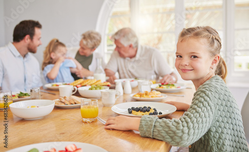 Girl child  portrait and breakfast with family  smile and morning in home with diet  nutrition or eating. Kid  plate and happy for fruit  juice and relax in home dining room  parents and grandparents