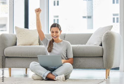 Winner woman, laptop and fist on floor for success, goal or bonus in trading, stock market or deal. Girl, computer and happy in home living room for cheers, invest or yes for profit, revenue or lotto photo
