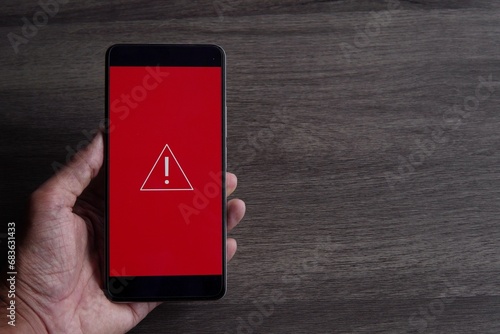 Smartphone with triangle caution warning icon. Copy space for text. System error, malware and cyber crime concept.