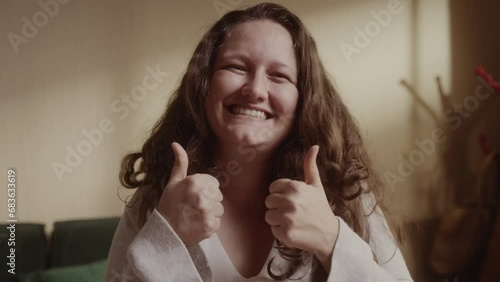 Mulher de cabelos ondulados sorrindo e fazendo sinal de positivo. Cinematico 4k. photo