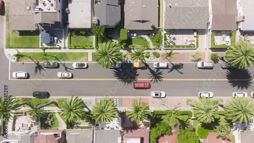 Overhead shot of Newport Beach avenue with summer traffic, Corona Del Mar, California, West Coast, USA. Top view of cars moving on street with luxury residential houses. City landscape with palm trees
