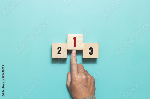 A man pushing wooden cube with the number one for task priority and management. Set work priority, arrange to do list. Concept of success,winner, victory or top ranking photo