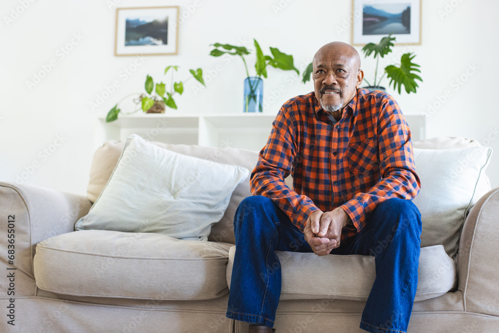 African american senior man sitting on sofa in sunny living room with copy space