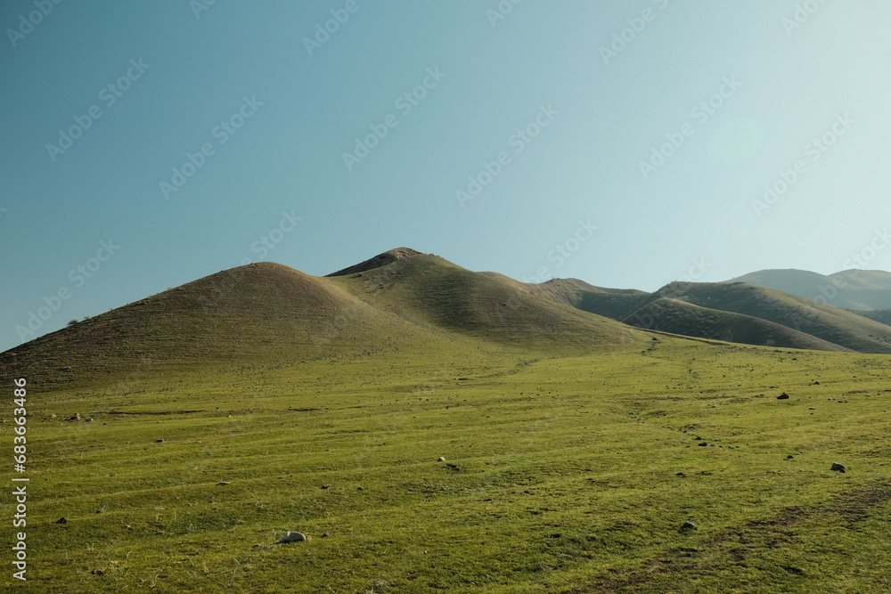 Obraz premium Grass-covered hills against a blue sky
