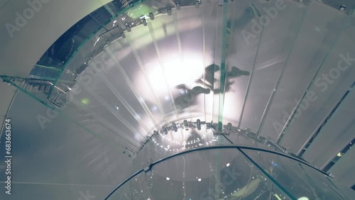 Rotating glass stairs and silhouettes of people