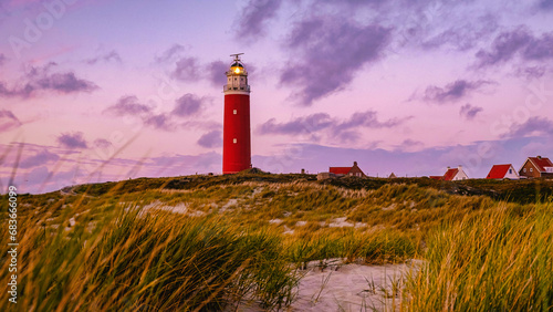 Texel lighthouse during sunset Netherlands Dutch Island Texel Holland during summer evening with sand dunes on the foreground photo