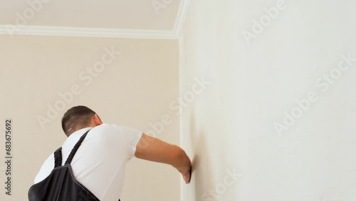 Textured vinyl wallpaper installation with special squeegee tool. Apartment remodeling.