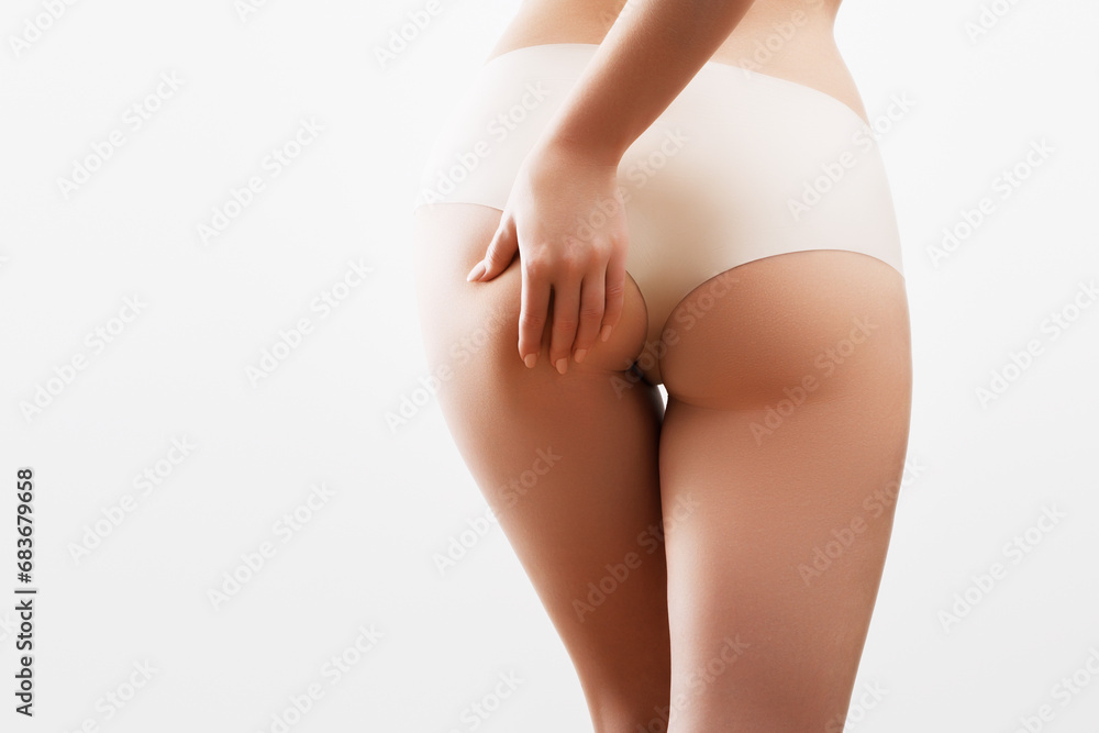 Beauty body. Young woman with beautiful buttocks. Slim girl in white lingerie posing at the studio. Back view of a female butt