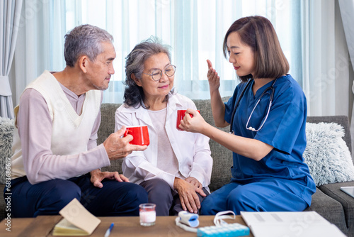 Senior couple get medical advice visit from caregiver nutritionist at home while having suggestion on herbal hot chamomile tea drink for longevity, healthy sleep and cure to insomnia