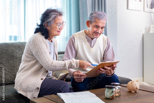 Senior Asian couple is planning on retirement saving fund looking at their income and expense and annual pension after taxes for elder long term financial investment and budget concept photo
