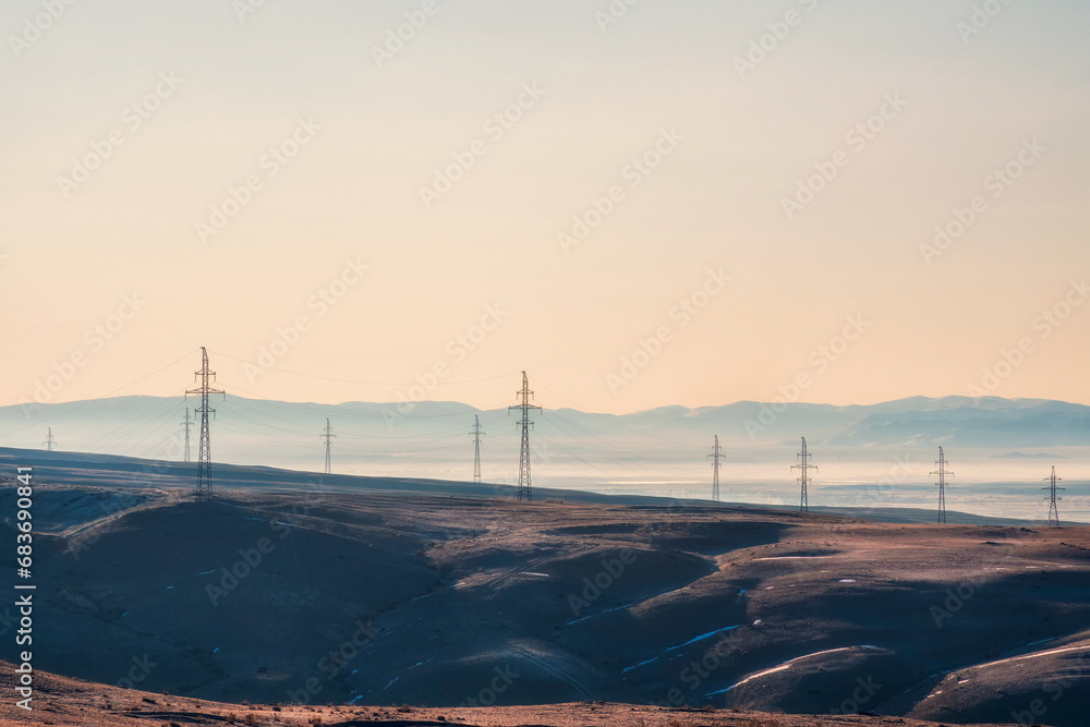 High voltage electric pole on mountain hill among remote wilderness in the sunrise at rural scene of Altai region.