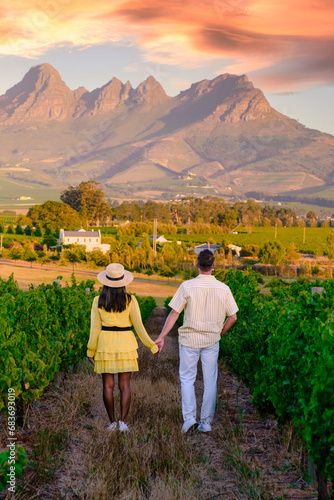 Couple of men and women at a Vineyard landscape at sunset with mountains in Stellenbosch, Cape Town, South Africa. wine grapes on the vine in the vineyard of Stellenbosch Western Cape South Africa photo