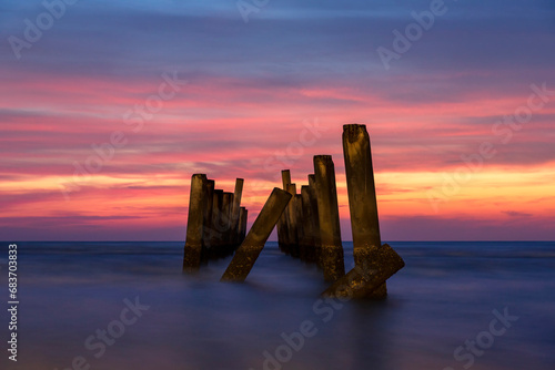 Scenery view of the concrete columns of the old port with Beautiful sky sunrise on Sao Iang Beach at Phetchaburi province. Long exposure picture 