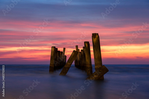 Scenery view of the concrete columns of the old port with Beautiful sky sunrise on Sao Iang Beach at Phetchaburi province. Long exposure picture  photo