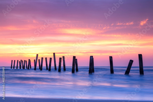 Scenery view of the concrete columns of the old port with Beautiful sky sunrise on Sao Iang Beach at Phetchaburi province. Long exposure picture 