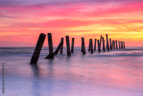 Scenery view of the concrete columns of the old port with Beautiful sky sunrise on Sao Iang Beach at Phetchaburi province. Long exposure picture  photo