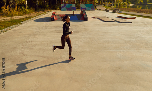 Top view of joyful young sporty woman running in a city park. Brunette girl wearing sportswear jogging outdoors. Weight loss, healthy lifestyle, sport workout and fitness in nature concept.