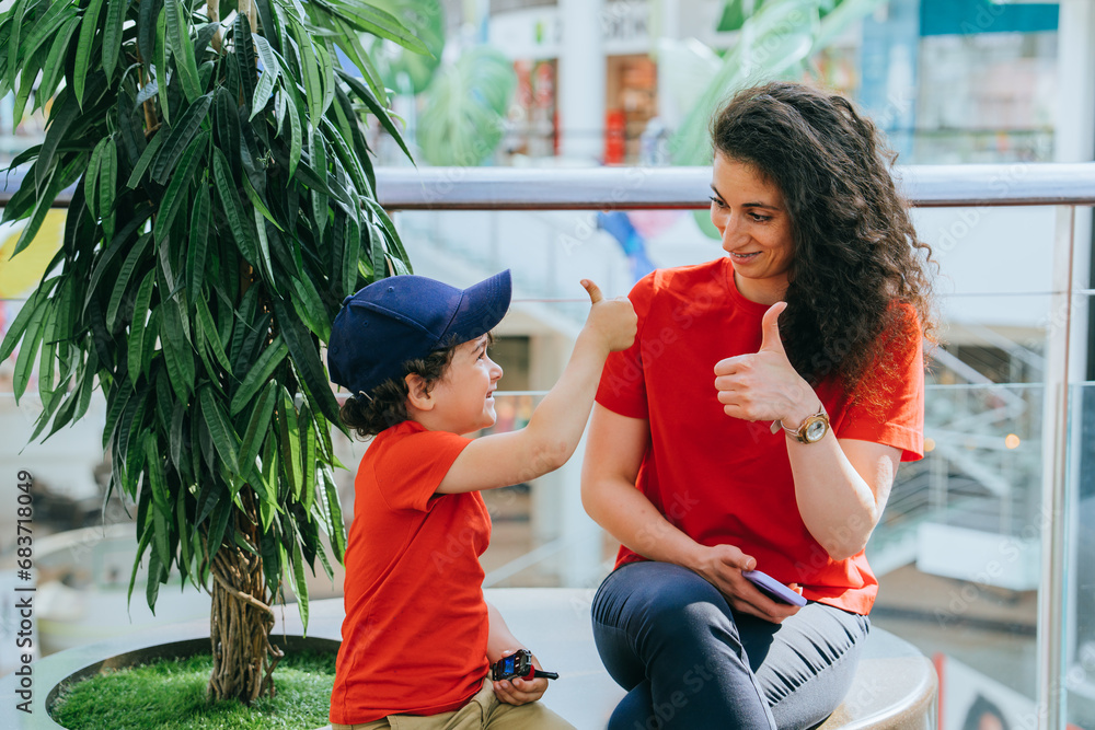 Happy little boy in baseball cap and red tshirt shows thumb up to